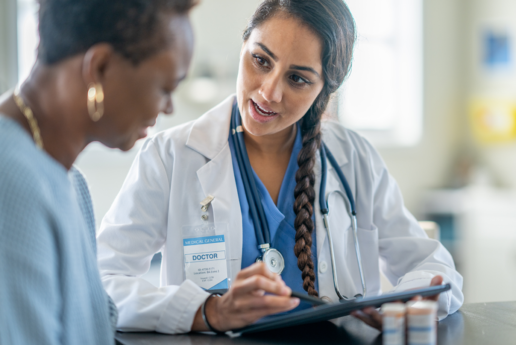 dermatologist speaking with patient, looking at tablet