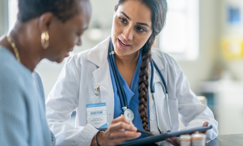 dermatologist speaking with patient, looking at tablet